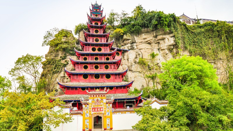 en pagode i r�dt som st�r inntil fjellvggen med tr�r rundt