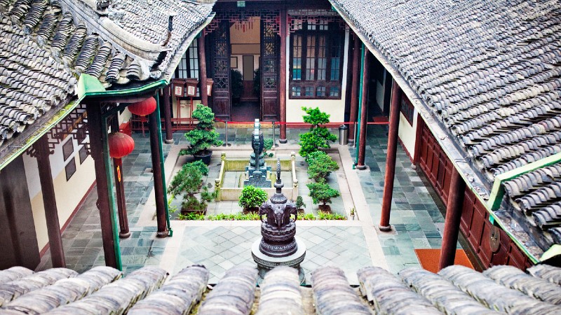 hustak og utsikt ned mot innerg�rden til tempelet i Shanghai. Hustak, bakg�rd, planter og vakre detaljer i byggverket