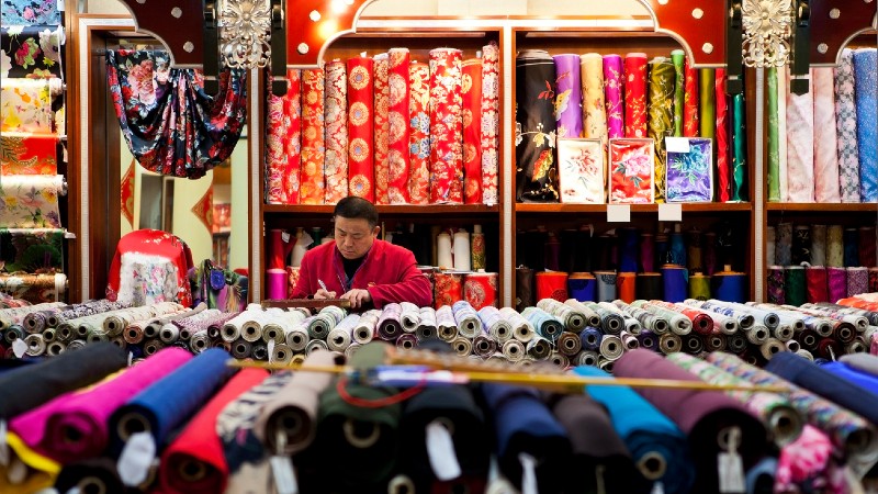 Silkebutikk med mange ruller silke, m�leb�nd og en mann