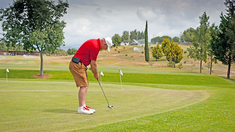 Man i r�d skjorte trener p� golfputting i Marbella.